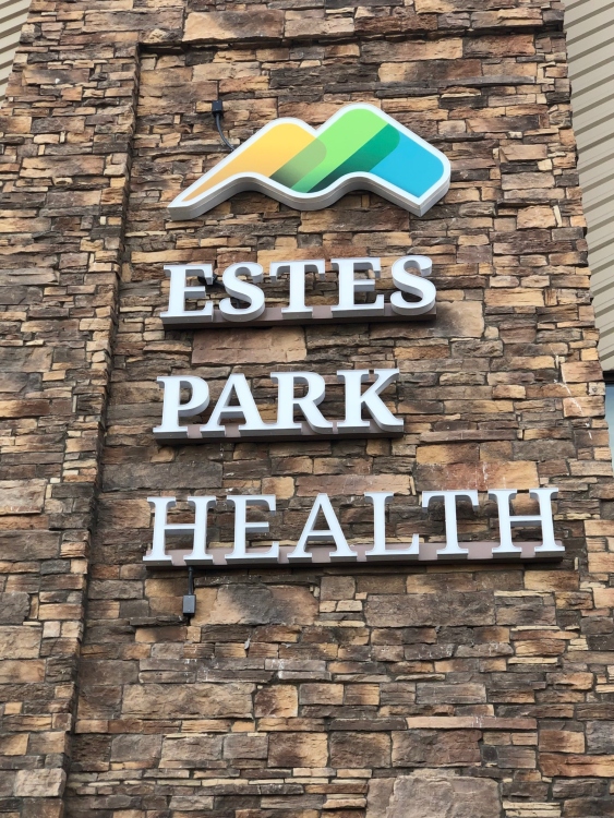 Sign on a stone wall displaying the logo and name 