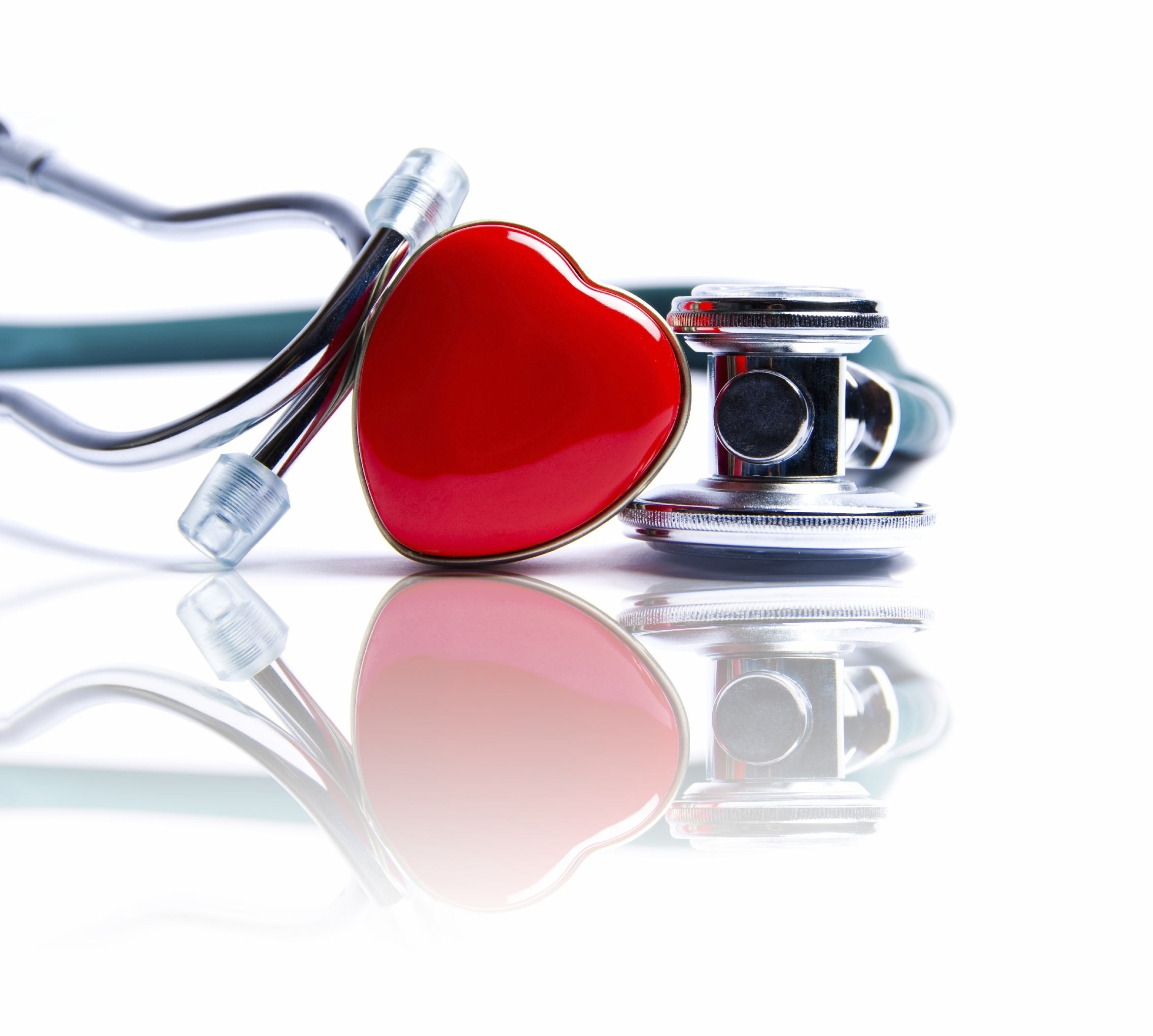 A stethoscope with a red heart-shaped decoration lies on a reflective surface.