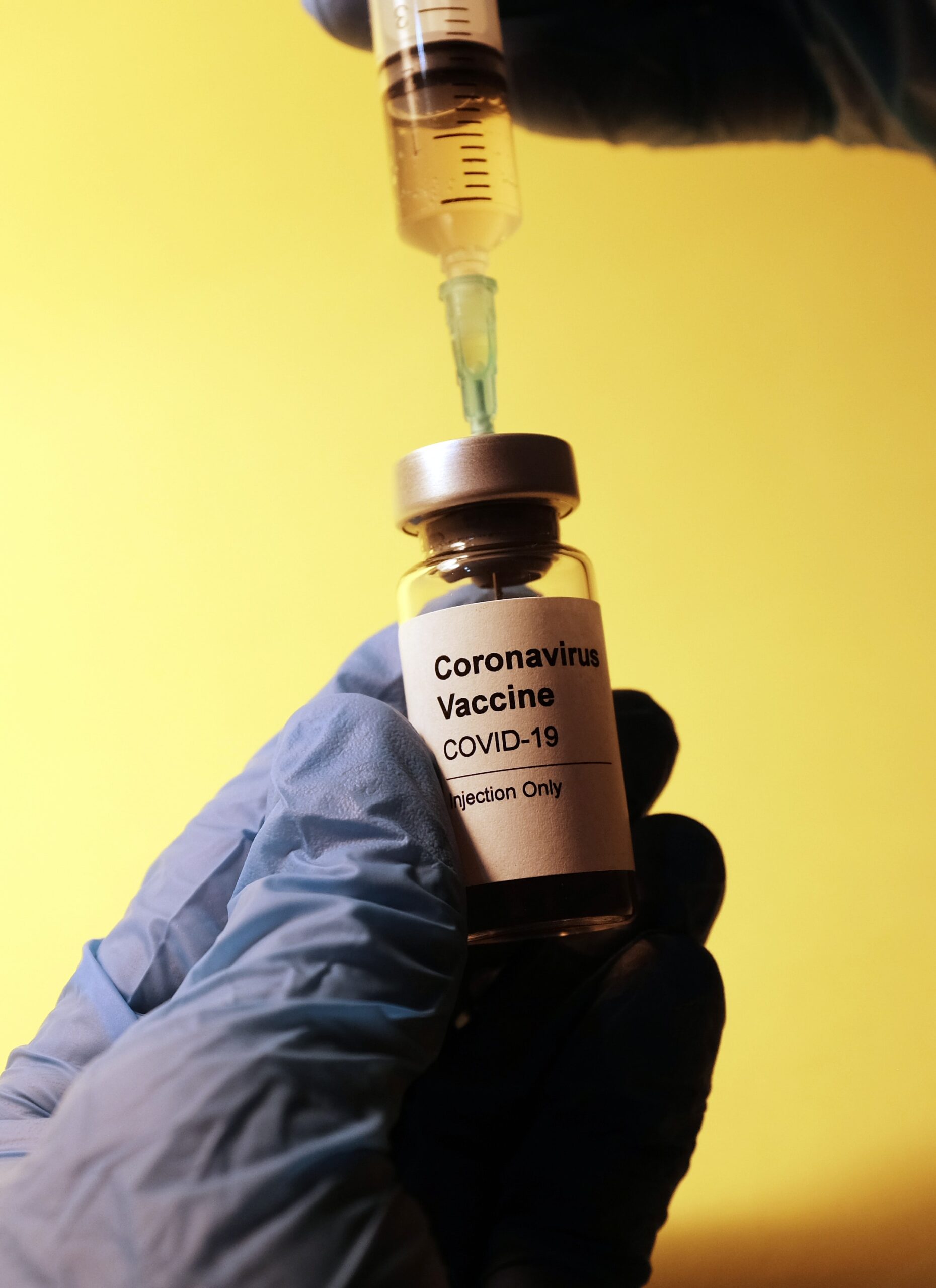 A gloved hand holds a vial labeled 