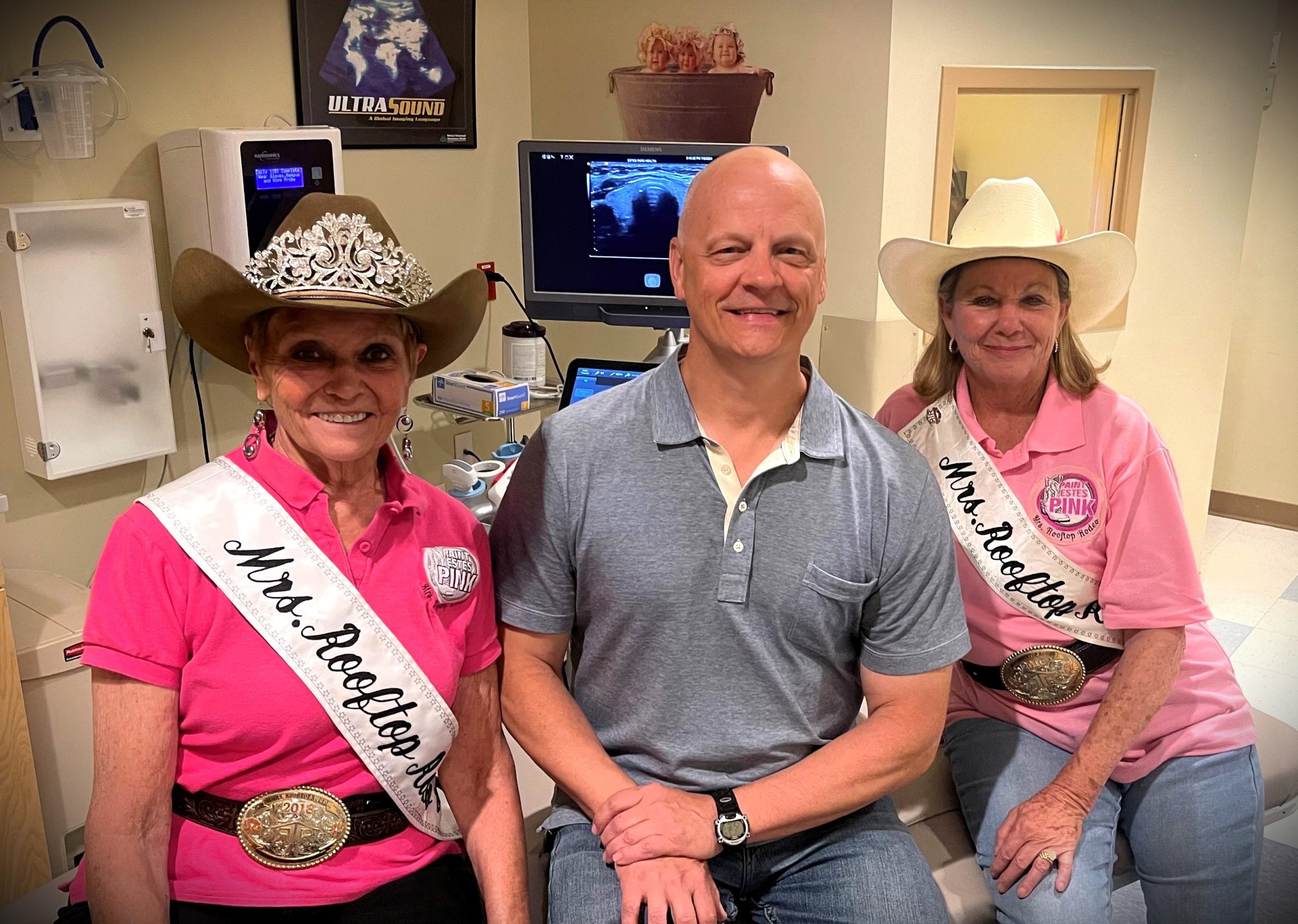Two women wearing white cowboy hats and pink shirts with 