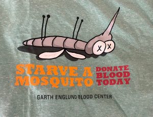 A T-shirt design featuring a cartoon mosquito lying on its back with the text "Starve a Mosquito, Donate Blood Today" and "Garth Englund Blood Center.