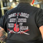 Person with tattoos on arms wears a black shirt with the text "Rock N' Roll Ain't Never Paid My Bills" and an image of a red electric guitar.