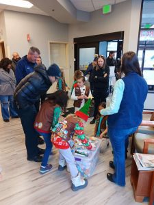 A group of Girl Scouts is sorting through donations in a lobby. Adults observe and assist.