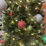 A decorated Christmas tree with red, green, and silver baubles, and warm white lights.