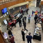 People gathered in a lobby with tables of food for a buffet-style event.