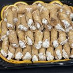 A tray filled with stacked cannoli, featuring crispy shells and creamy fillings.