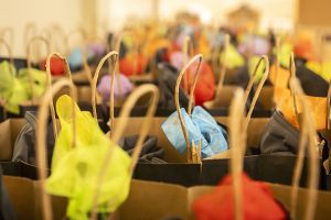 A close-up view of several gift bags arranged in rows, each with tissue paper of various colors sticking out of the top.